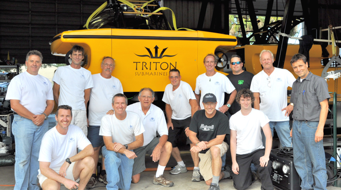 A crew from Triton Submarines in front of the Triton 3300/3 submersible which will dive to 3,300 feet with three people aboard.
