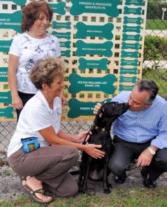 Star Dancer Tony Donadio kisses Kelly a lab mix service dog at the DFL Dog Park. With Tony are Shelly Ferger (kneeling) and Kelly’s owner Norine.