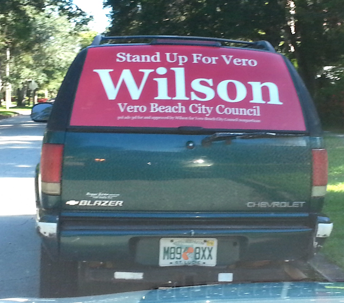 A campaign sign mounted in the back window of Wilson's vehicle failed to include the require word "For" between his name and the office he is seeking.  The inclusion of "For" is required by Florida campaign low to prevent challengers, such as Wilson, from creating the false impression they are incumbents. 