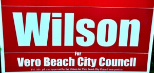 Wilson's campaign signs now include the required word "For" between his name and the office he is seeking.