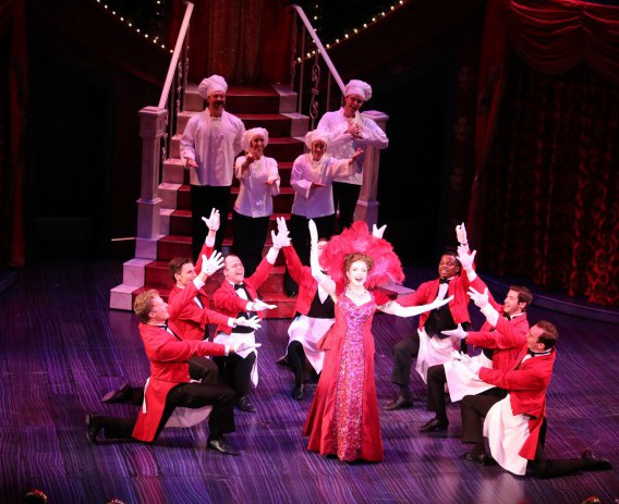 Wait and kitchen staff welcome Dolly back to the Harmonia Gardens.